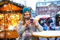 Beautiful young woman drinking hot punch, mulled wine on German Christmas market. Happy girl in winter clothes with Royalty Free Stock Photo