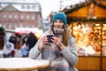 Beautiful young woman drinking hot punch, mulled wine on German Christmas market. Happy girl in winter clothes with Royalty Free Stock Photo