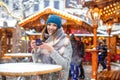 Beautiful young woman drinking hot punch, mulled wine on German Christmas market. Happy girl in winter clothes with Royalty Free Stock Photo