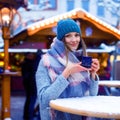 Beautiful young woman drinking hot punch, mulled wine on German Christmas market. Happy girl in winter clothes with Royalty Free Stock Photo