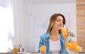 Beautiful young woman drinking orange juice at table indoors, space for text Royalty Free Stock Photo