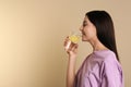 Beautiful young woman drinking tasty lemon water on beige background. Space for text Royalty Free Stock Photo