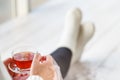 Beautiful young woman drinking tea and looking through window while sitting at windowsill at home Royalty Free Stock Photo