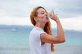 Beautiful young woman drinking water in summer beach outdoor with sea background Royalty Free Stock Photo