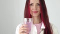 Beautiful young woman drinks electrolytes. Girl drinking rose water in a glass