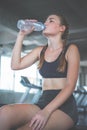 Beautiful young woman drinks water in gym. Sports nutrition concept Royalty Free Stock Photo