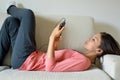 Beautiful young woman with earphones relaxing on the sofa, she is listening to music using a smart phone, chill out and leisure Royalty Free Stock Photo