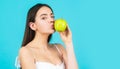Beautiful young woman eating an apple. Healthy lifestyle. Happy woman kiss apple on blue background
