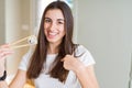 Beautiful young woman eating asian sushi using chopsticks with surprise face pointing finger to himself