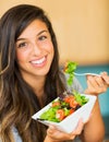 Beautiful young woman eating a bowl of healthy organic salad