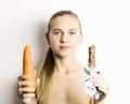 Beautiful young woman eating an carrot. carrot vs chocolate. healthy food - strong teeth concept Royalty Free Stock Photo
