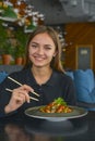 Beautiful young woman eating chinese food called Wok with chopsticks. Wok with meat and fried asparagus in a plate Royalty Free Stock Photo