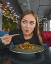 Beautiful young woman eating chinese food called Wok with chopsticks. Wok with meat and fried asparagus in a plate Royalty Free Stock Photo