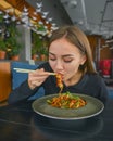 Beautiful young woman eating chinese food called Wok with chopsticks. Wok with meat and fried asparagus in a plate Royalty Free Stock Photo