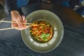 Beautiful young woman eating chinese food called Wok with chopsticks. Wok with meat and fried asparagus in a plate Royalty Free Stock Photo