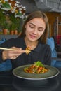 Beautiful young woman eating chinese food called Wok with chopsticks. Wok with meat and fried asparagus in a plate Royalty Free Stock Photo