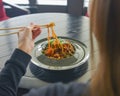 Beautiful young woman eating chinese food called Wok with chopsticks. Wok with meat and fried asparagus in a plate Royalty Free Stock Photo