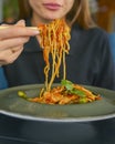 Beautiful young woman eating chinese food called Wok with chopsticks. Wok with meat and fried asparagus in a plate Royalty Free Stock Photo