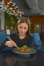 Beautiful young woman eating chinese food called Wok with chopsticks. Wok with meat and fried asparagus in a plate Royalty Free Stock Photo