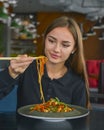 Beautiful young woman eating chinese food called Wok with chopsticks. Wok with meat and fried asparagus in a plate Royalty Free Stock Photo