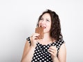Beautiful young woman eating a chocolate bar, wears a dress with polka dots Royalty Free Stock Photo