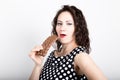 Beautiful young woman eating a chocolate bar, wears a dress with polka dots. expresses different emotions Royalty Free Stock Photo