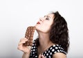 Beautiful young woman eating a chocolate bar, wears a dress with polka dots. expresses different emotions Royalty Free Stock Photo