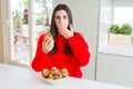 Beautiful young woman eating chocolate chips muffins cover mouth with hand shocked with shame for mistake, expression of fear, Royalty Free Stock Photo