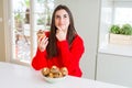 Beautiful young woman eating chocolate chips muffins serious face thinking about question, very confused idea Royalty Free Stock Photo