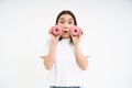 Beautiful young woman eating delicious glazed dougnuts, holding two pink donuts and smiling, white background Royalty Free Stock Photo