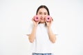 Beautiful young woman eating delicious glazed dougnuts, holding two pink donuts and smiling, white background Royalty Free Stock Photo