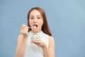 Beautiful young woman eating fresh yoghurt, raisins and oatmeal for breakfast