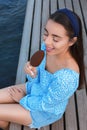 Beautiful young woman eating ice cream glazed in chocolate near river Royalty Free Stock Photo