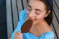 Beautiful young woman eating ice cream glazed in chocolate on pier, closeup Royalty Free Stock Photo
