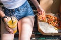 Beautiful, young woman eating pizza and fries in the street. The concept of fast food, food delivery and lunch in nature Royalty Free Stock Photo