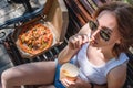 Beautiful, young woman eating pizza in the street. The concept of fast food, food delivery and lunch in nature Royalty Free Stock Photo