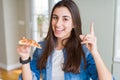 Beautiful young woman eating a slice of tasty pizza very happy pointing with hand and finger to the side Royalty Free Stock Photo