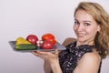 Beautiful young woman eating an vegetables. holding a plate with vegetables, red pepper, tomato, cucumber. healthy food Royalty Free Stock Photo