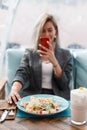 Beautiful young woman eats and takes photo food in a restaurant.