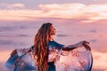 Beautiful young woman in elegant dress on the beach at sunset