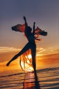 beautiful young woman in elegant dress dancing on water at sunset Royalty Free Stock Photo