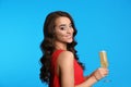 Beautiful young woman in elegant dress holding glass of champagne on blue background. Christmas party Royalty Free Stock Photo