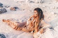 Beautiful young woman in elegant dress lying on sand at the beach at sunset Royalty Free Stock Photo