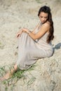 Beautiful young woman in elegant dress sitting on the beach at sunset Royalty Free Stock Photo