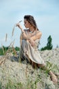 Beautiful young woman in elegant dress sitting on the beach at sunset Royalty Free Stock Photo