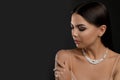 Beautiful young woman with elegant jewelry on dark. Space for text Royalty Free Stock Photo