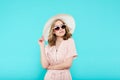 Beautiful young woman in elegant pale pink dress, sunglasses and summer hat. Studio portrait of fashionable woman.