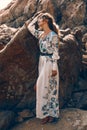 Beautiful young woman in elegant stylish dress on stone beach at sunset Royalty Free Stock Photo