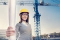 A beatiful young woman engineer is standing with her arms crossed in front of a construction crane