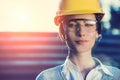 A beautiful young woman engineer is in front of a construction metal wall wearing protective gear, helmet and glasses. Royalty Free Stock Photo